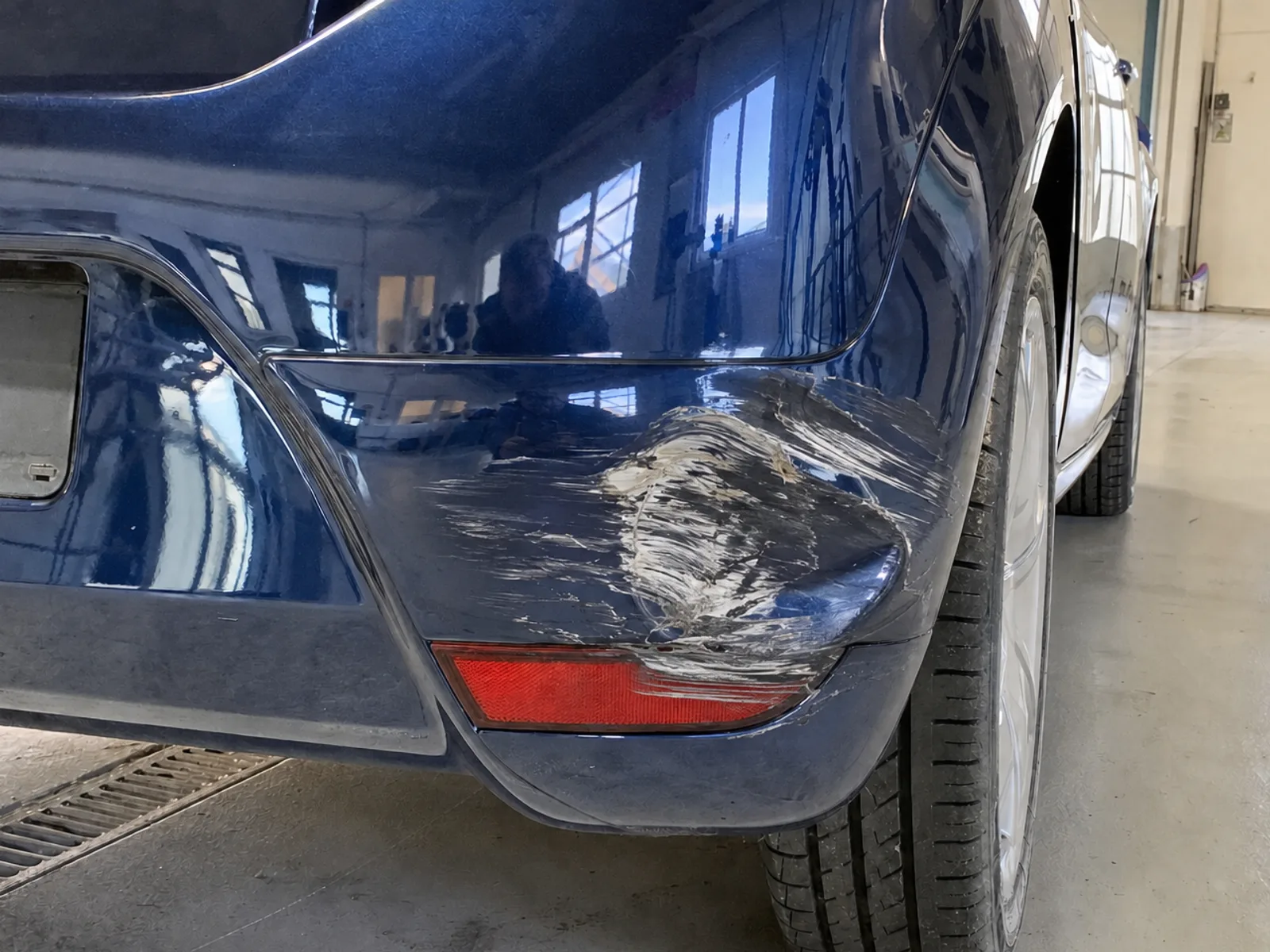 Zerkratzte Stoßstangenecke eines blauen Autos vor der Smart-Repair-Reparatur