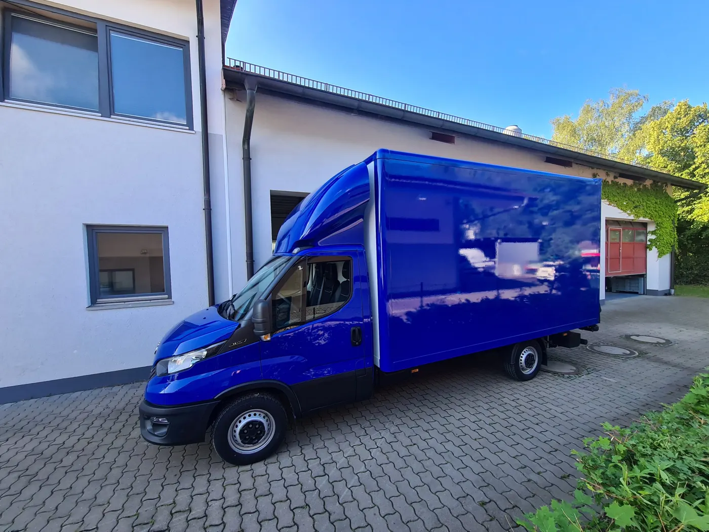 Blau lackierter Koffer-LKW vor dem Betrieb am Klausnerring