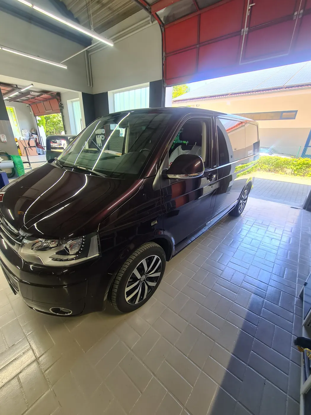 Schwarzer VW-Bus nach der Lackierung in der Halle