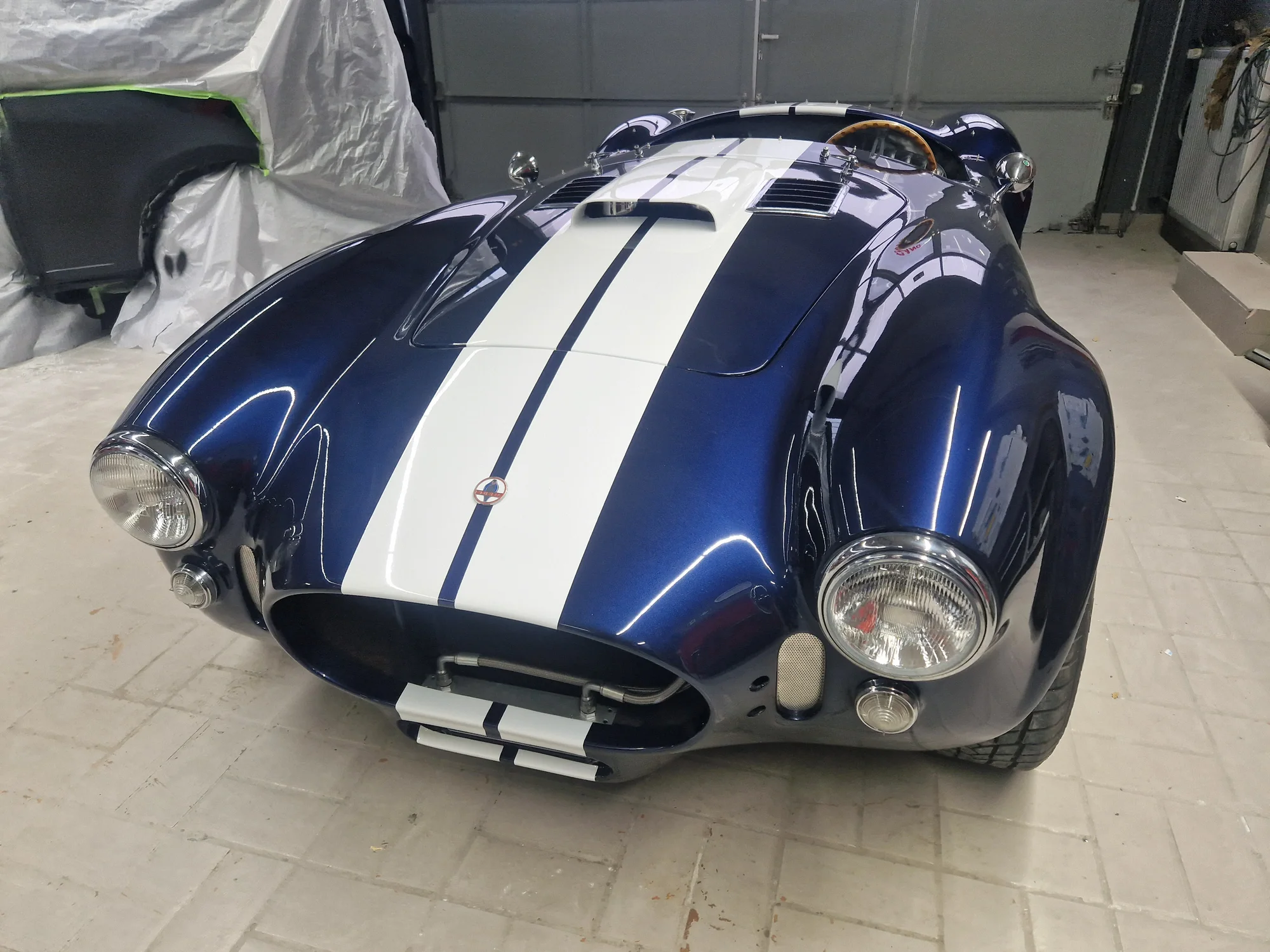 Front des blauen Cobra-Roadsters mit weißen Streifen, Schrägansicht