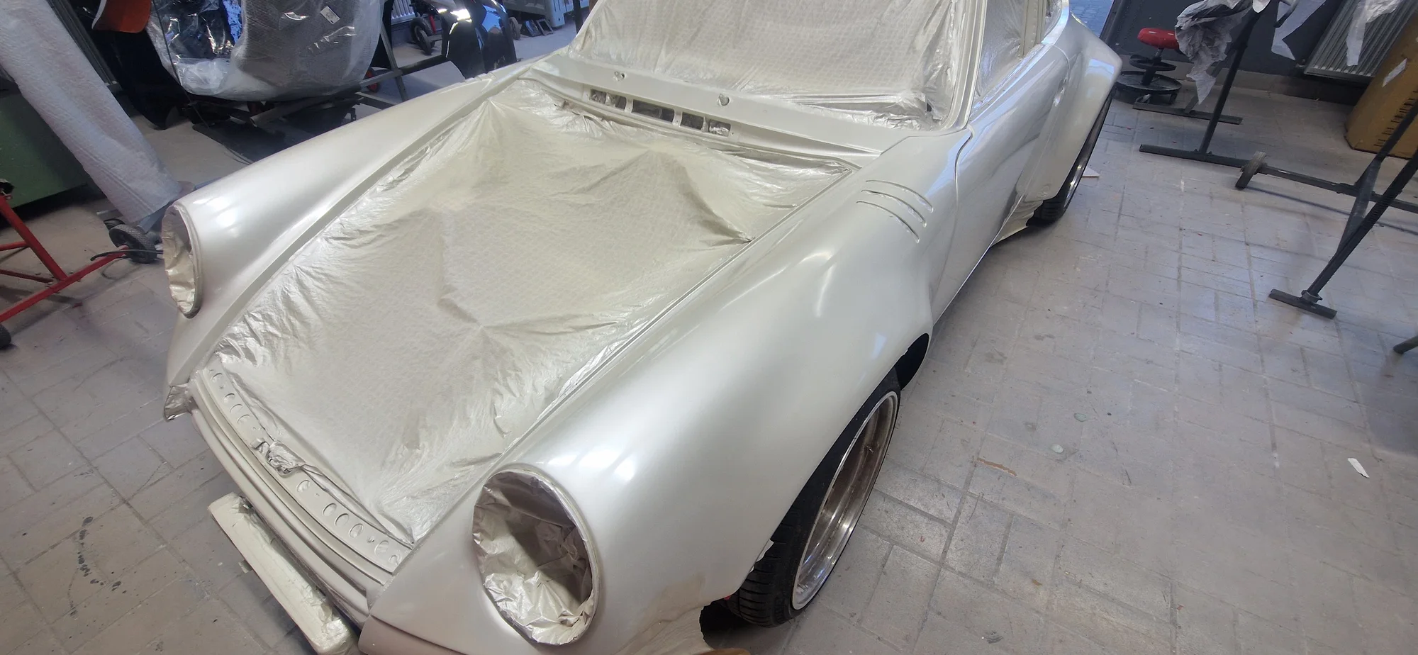 Porsche 911 mit abgedeckter Fronthaube vor der Halle der Lackprofi GmbH