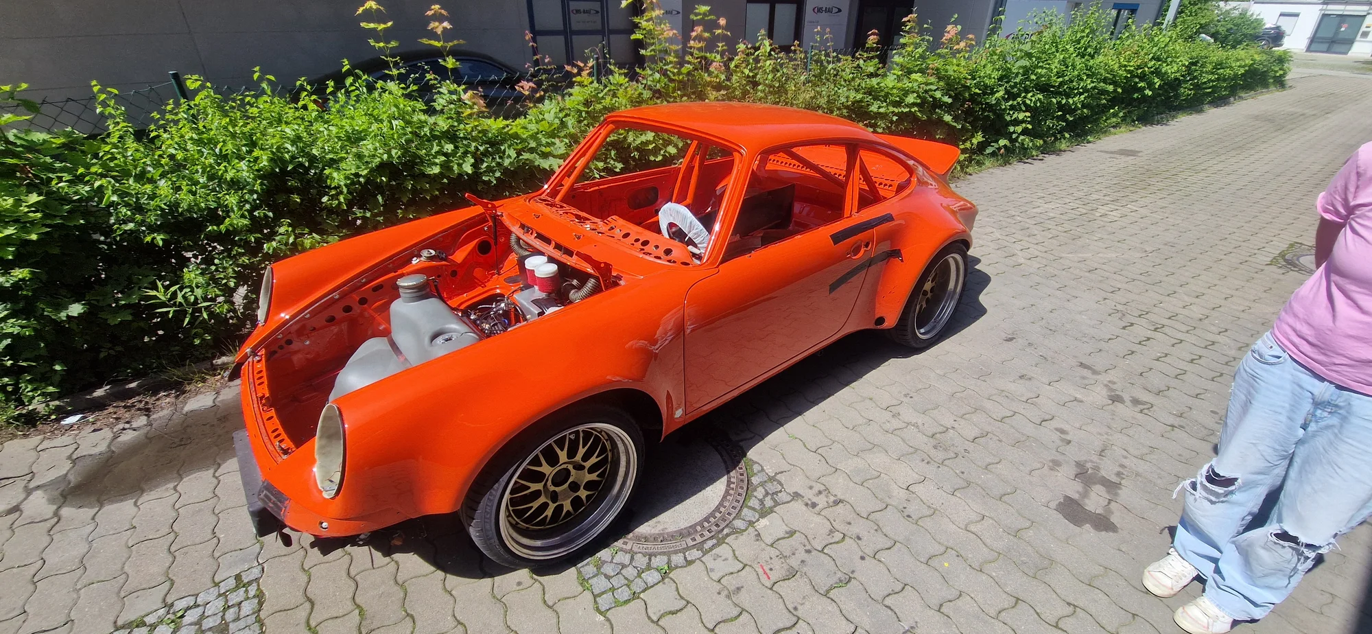 Orange Karosserie eines Porsche 911 während der Arbeit vor der Werkstatt